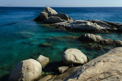 Rocks on shore by sea against sky