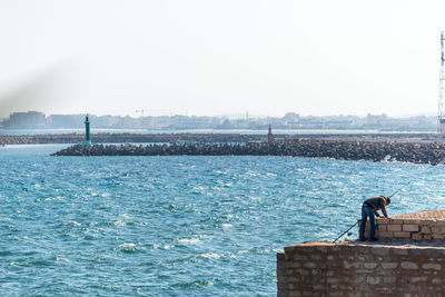 Man on horse by sea against clear sky