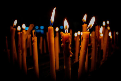 Close-up of burning candles against black background