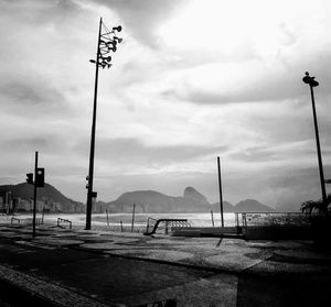 Street lights by river against sky