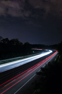 Light trails on road against sky at night