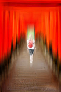 Rear view of person walking on red building