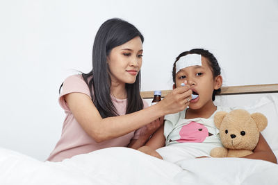 Mother giving syrup of ill daughter at home