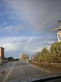 Rainbow over road in city against sky