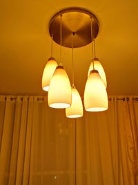 Low angle view of illuminated light bulb hanging on ceiling