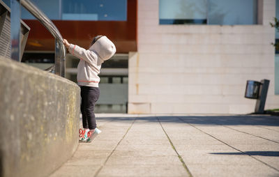 Girl standing on footpath in city