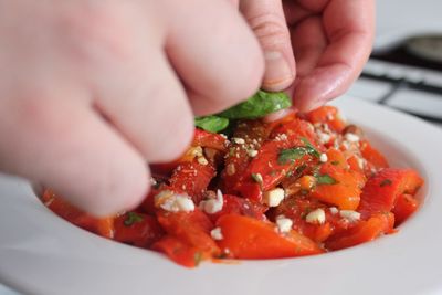 Cropped hands of person preparing antipasto in plate