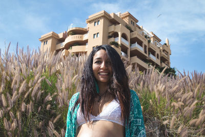 Portrait of smiling young woman standing against the sky