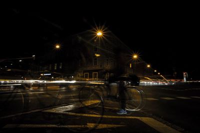 Illuminated city street against sky at night