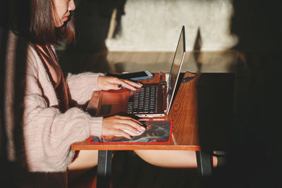 Woman using mobile phone while sitting on table