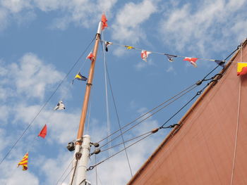 Low angle view of flags hanging on mast against sky