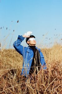 Man sitting on chair in field against clear blue sky