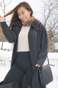 Portrait of smiling young woman standing in snow