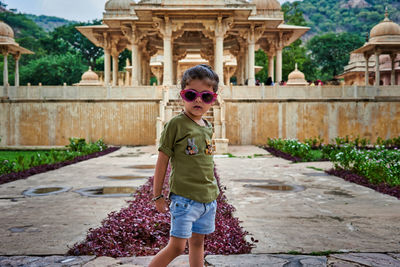 Portrait of girl wearing sunglasses while standing against historic building