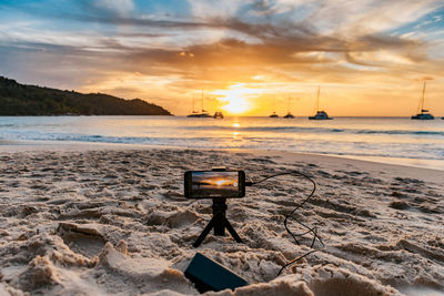 Mobile phone on a tripod recording video of a sunset over ocean. tropical sandy beach.