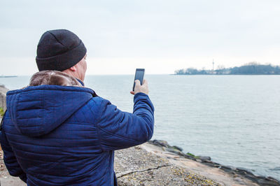 Man photographing sea through mobile phone