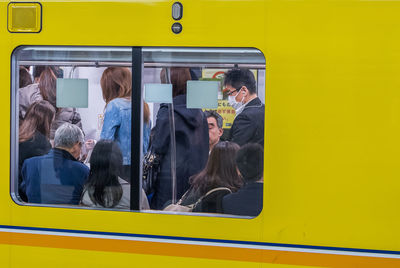 People in yellow train seen through window