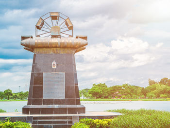 Tower on field by lake against sky