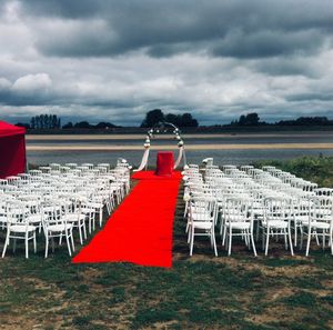 Empty chairs on beach against sky