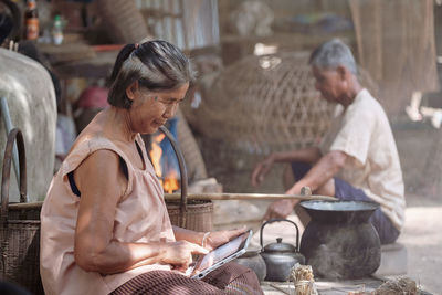 Side view of senior woman using digital tablet while sitting outdoors