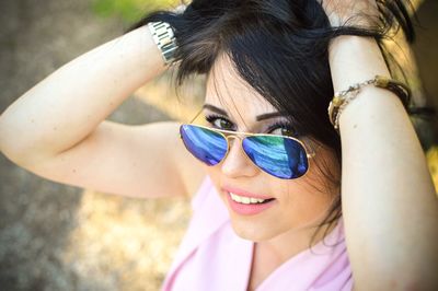 Portrait of young woman with hands in hair wearing sunglasses