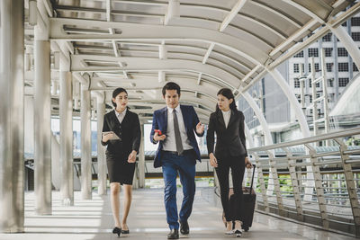 Full length of business people walking in office corridor