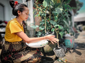 Side view of young woman holding umbrella