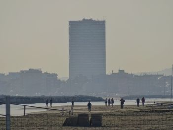 People on city buildings against clear sky