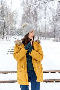 Woman standing in snow against trees during winter