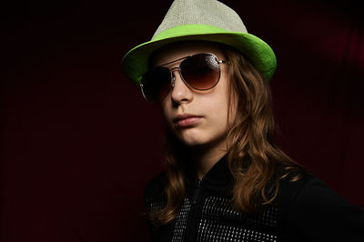 Portrait of young woman wearing sunglasses against black background