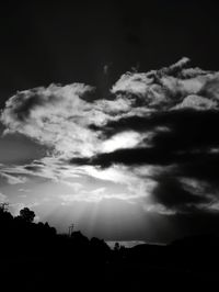 Low angle view of storm clouds over silhouette landscape