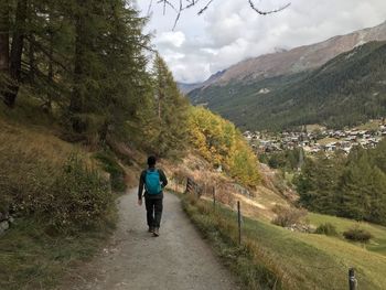 Rear view of man walking on mountain against sky