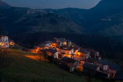 High angle view of buildings and mountains against sky at night