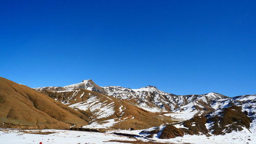 Scenic view of snowcapped mountains against clear blue sky