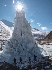 People on snowcapped mountain against sky during winter
