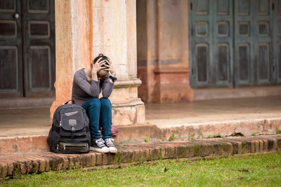 Full length of man sitting outside building