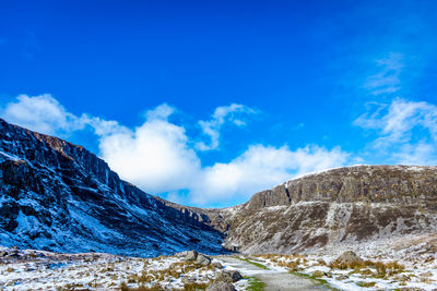 Scenic view of snowcapped mountains against blue sky