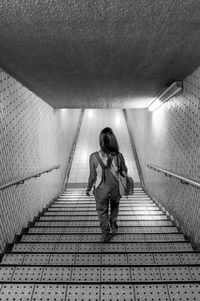 Rear view full length of woman moving down on steps at subway station