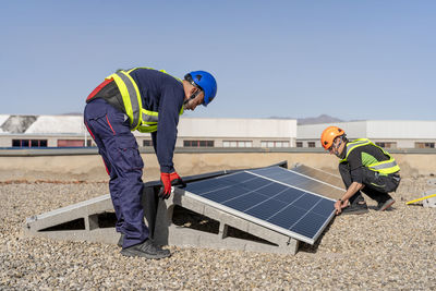 Engineers installing solar panel on sunny day