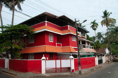 Red house by road against sky in city