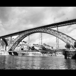 Bridge over river against cloudy sky