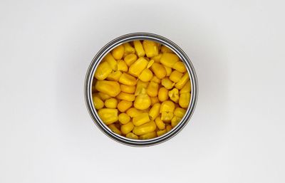 High angle view of yellow eggs in bowl against white background