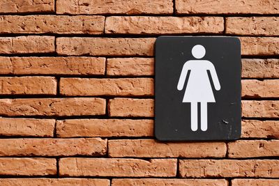 Close-up of arrow sign on brick wall