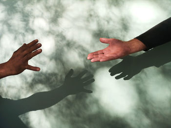 Cropped hands against wall with sunlight