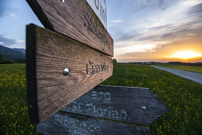 Information sign on field against sky during sunset