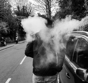 Man standing amidst smoke on road