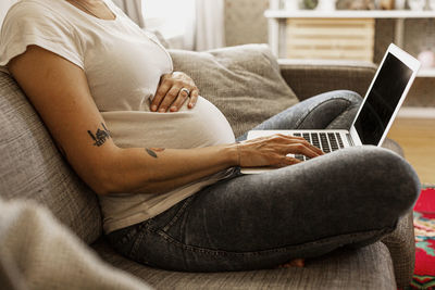 Mid section of pregnant woman using laptop