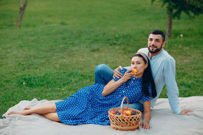 Portrait of smiling young couple sitting on grassy field