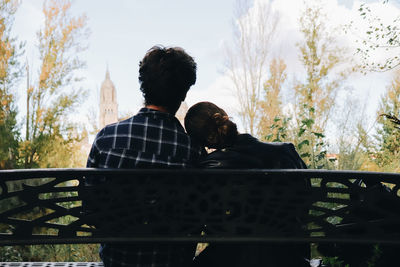 Rear view of man sitting on railing