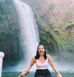 Portrait of smiling young woman in waterfall